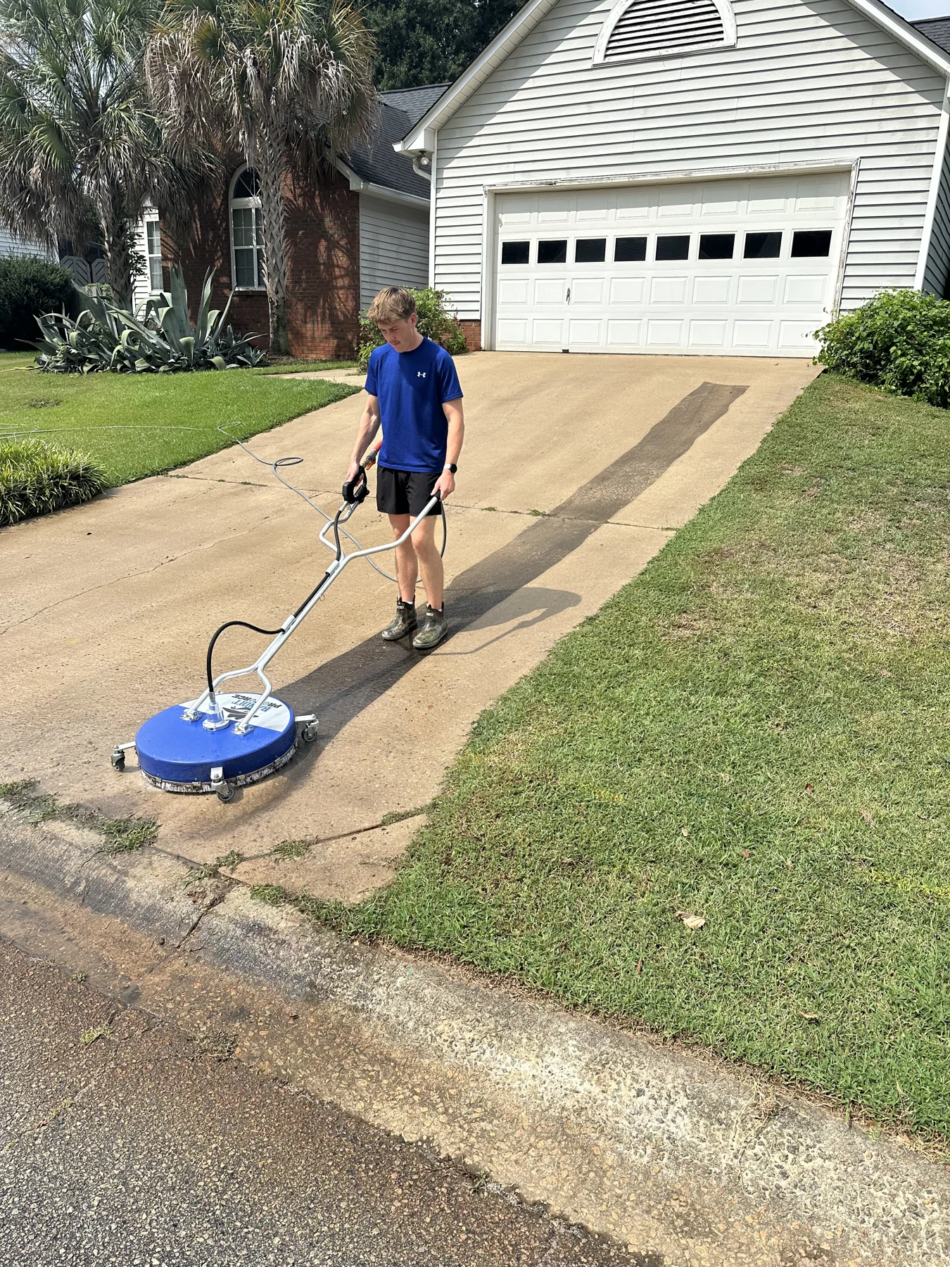 Andrew using a professional surface cleaner on a concrete driveway