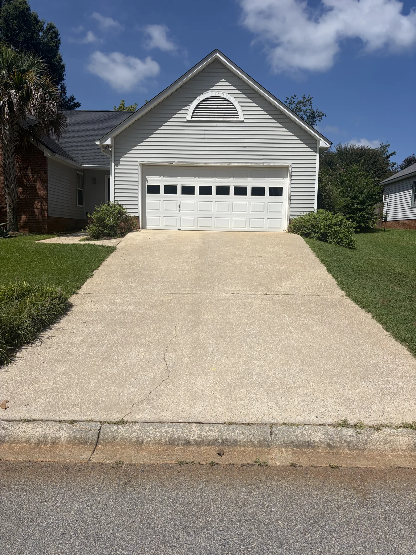Concrete driveway after cleaning, leading to a detached garage